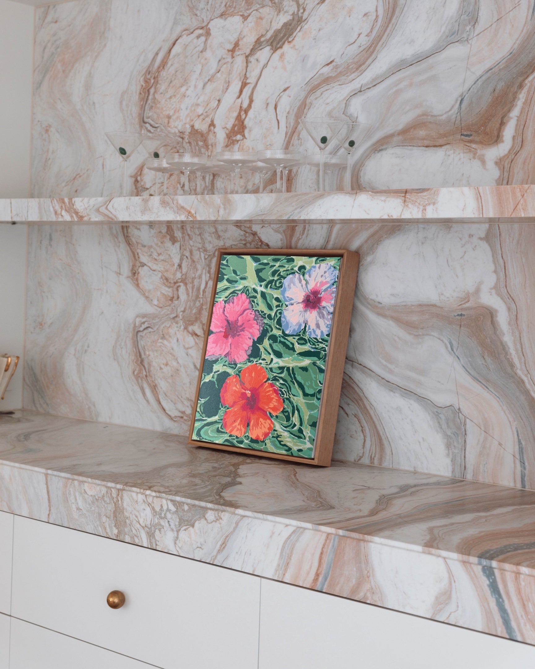Paint Like Frida’s Hibiscus Dreams Big Framed Canvas styled on a marble benchtop — tropical pink, purple, and orange hibiscus flowers floating in green swirls, framed in a custom wooden floating frame.