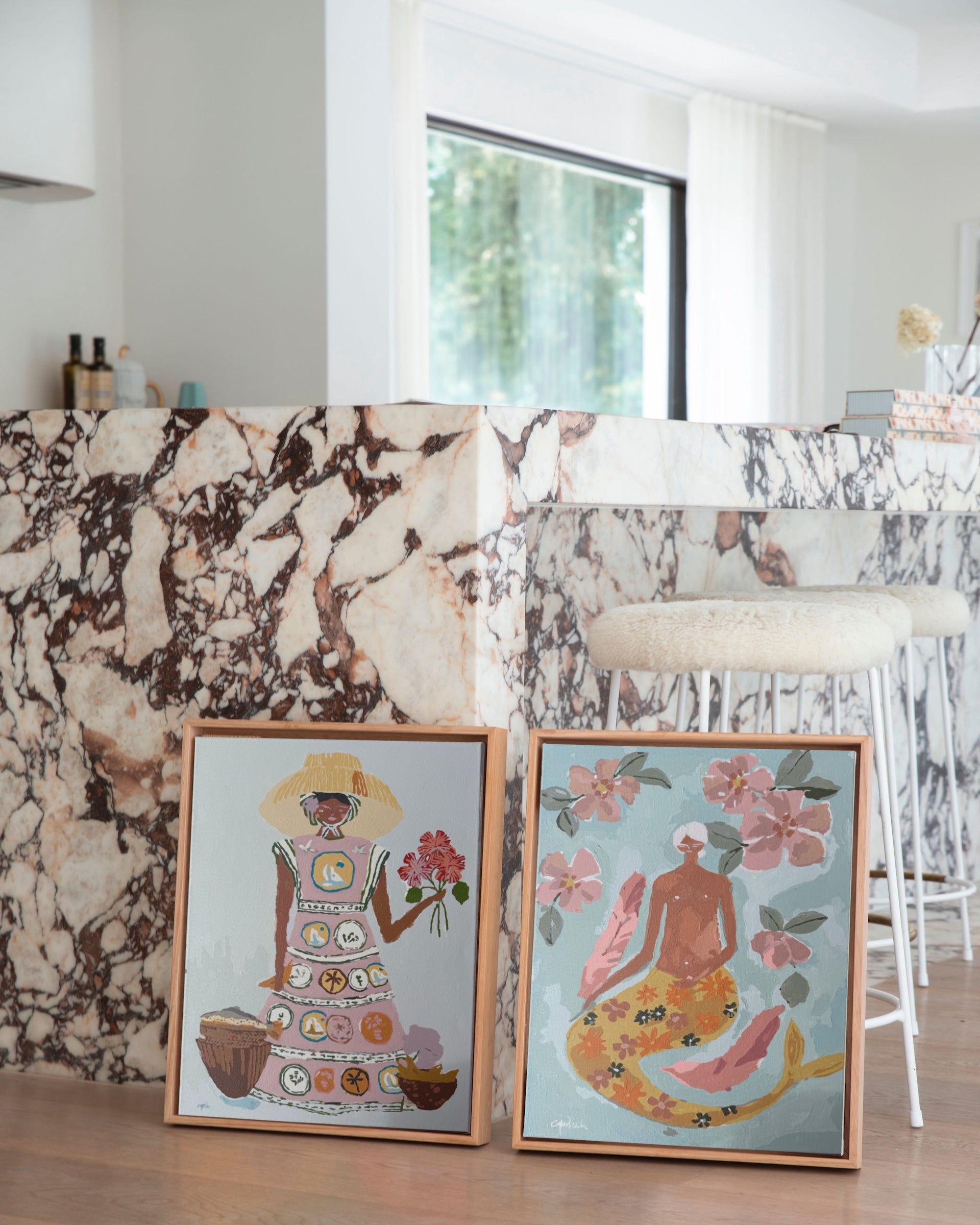 Paint Like Frida’s Lady of the Sea and Patience Big Framed Canvases, styled side by side against a marble kitchen island — both paint by numbers artworks in custom-made floating wooden frames, showcasing earthy tones and feminine charm.